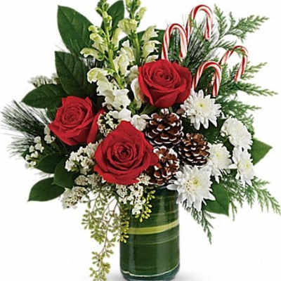 Red roses and white flowers in a green glass vase with candy canes and pinecones