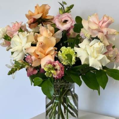 Mixed pastel flowers arranged in a clear glass vase