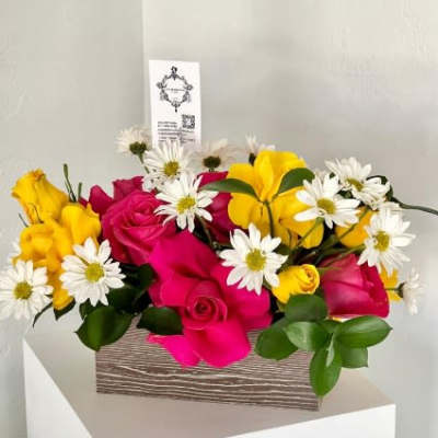 Pink and yellow roses with white daisies in a wooden box