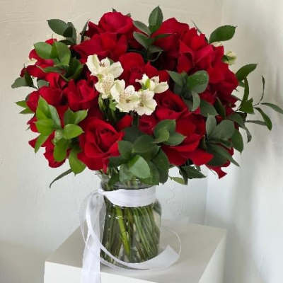 Bouquet of red roses with white flowers in a glass vase