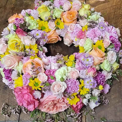 Heart-shaped bouquet of pastel roses and mixed flowers on a wooden surface