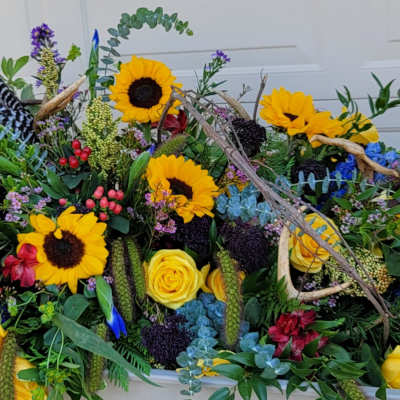 Large floral arrangement with sunflowers, yellow roses, and blue flowers