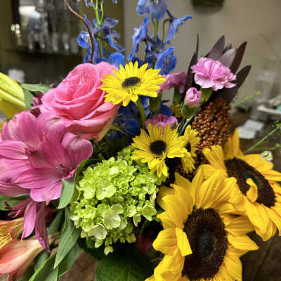 Mixed bouquet with sunflowers, pink roses, and blue delphinium
