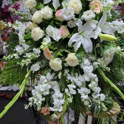 Large white floral standing spray with lilies and roses on an easel