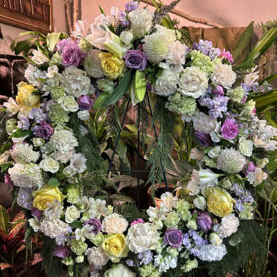 Large floral wreath with roses, lilies, and pastel blooms on a stand