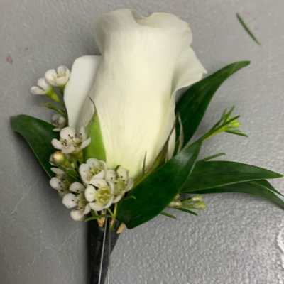 White calla lily boutonniere with small white blossoms and green leaves