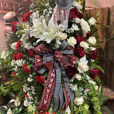 Large red, white, and black floral standing spray with ribbons and a houndstooth hat
