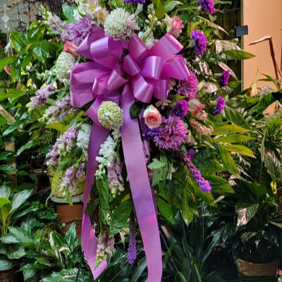 Large purple and pink floral standing spray with a ribbon bow