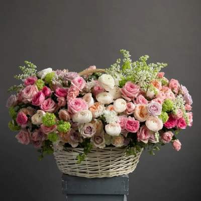 Large basket of pink and peach roses and ranunculus with soft white and green accents