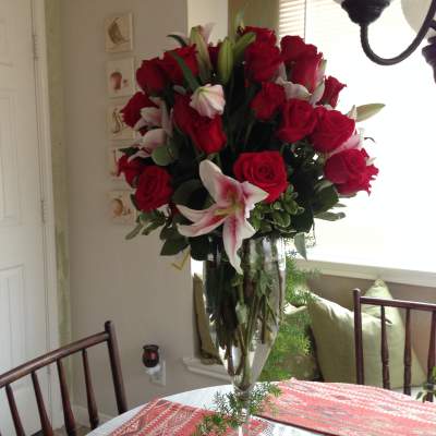 Tall bouquet of red roses and pink lilies in a clear glass vase