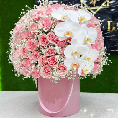 Pink roses and white orchids arranged in a pink hatbox