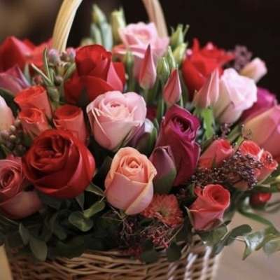 Basket of mixed roses and tulips in pink and red tones