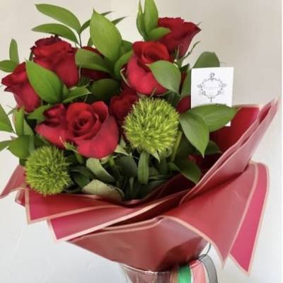 Bouquet of red roses with green accents wrapped in pink paper