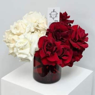 Red and white rose arrangement in a dark glass vase