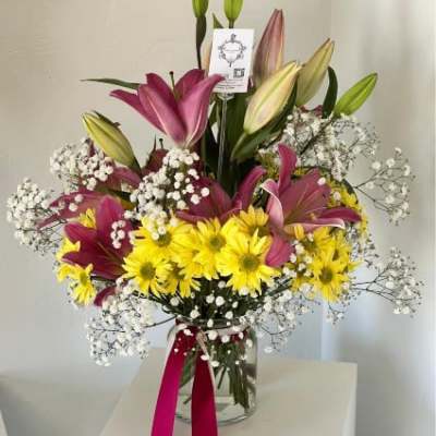 Bouquet of pink lilies and yellow daisies in a glass vase