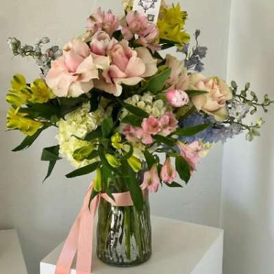 Pink and yellow mixed bouquet in a glass vase with a pink ribbon