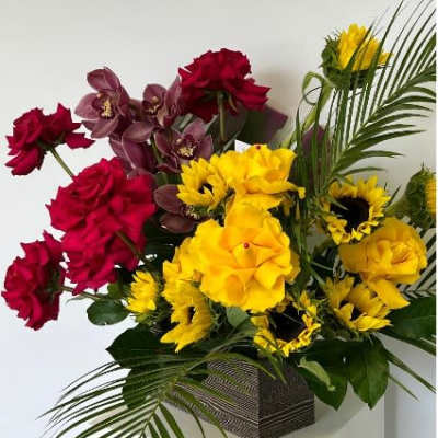Red and yellow floral arrangement in a square vase