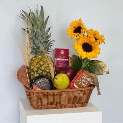 Gift basket with sunflowers, pineapple, fruit, crackers, and cheese