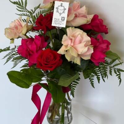 Bouquet of red and blush roses in a glass vase with a pink ribbon