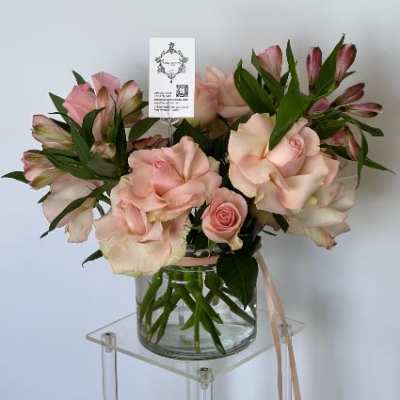 Pink roses and alstroemeria in a glass vase with a ribbon