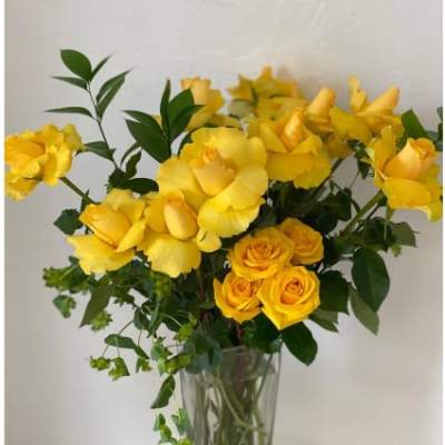 Yellow roses and yellow blooms in a clear glass vase