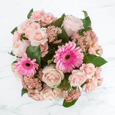 Round bouquet of pale pink roses and spray roses with bright pink gerbera daisies.