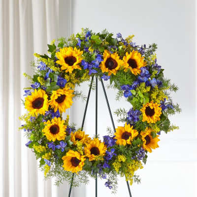 Standing wreath of yellow sunflowers and blue flowers on a metal easel