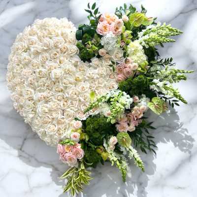 Heart-shaped floral arrangement of white and blush roses with green accents