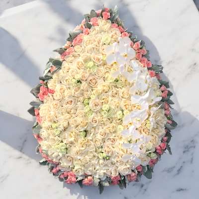 Large oval arrangement of cream and pink roses with white orchids