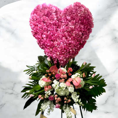 Heart-shaped pink floral tribute above a mixed flower spray