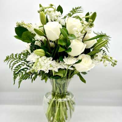 White roses and lilies arranged in a clear glass vase