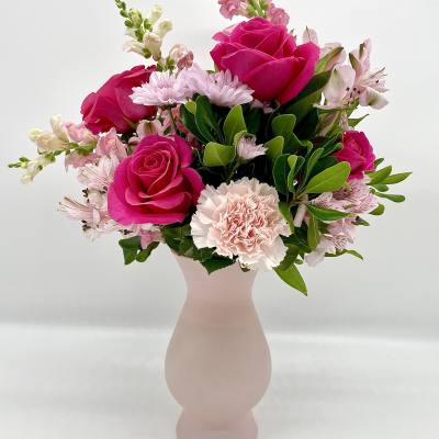 Pink roses and pale flowers arranged in a blush vase
