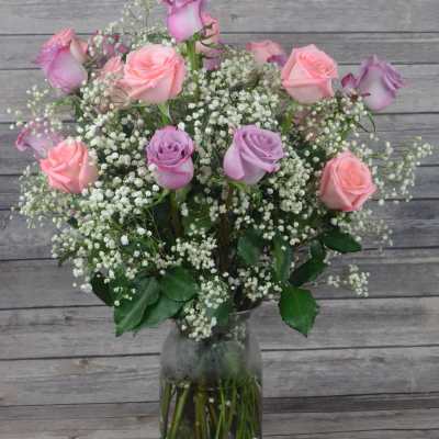 Pink and lavender roses in a clear glass vase with baby's breath