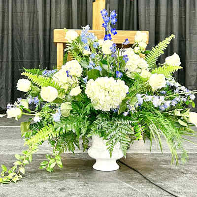 Large white and blue floral arrangement in a white urn