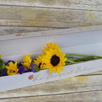 Sunflowers and purple filler flowers in a white gift box