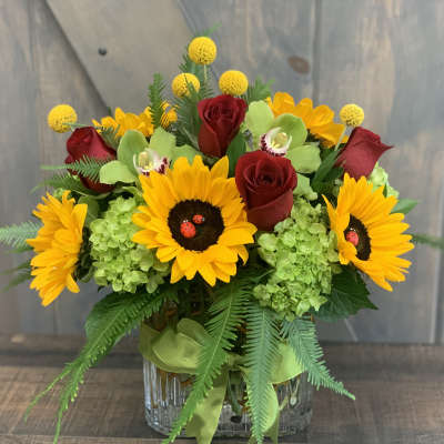 Bouquet of sunflowers and red roses in a glass vase