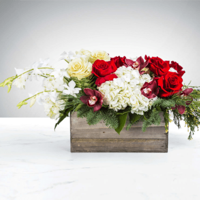 Low red and white rose arrangement with orchids and hydrangeas in a wooden box