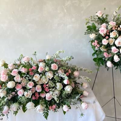 Pink and white rose arrangements, one on a table and one on a stand