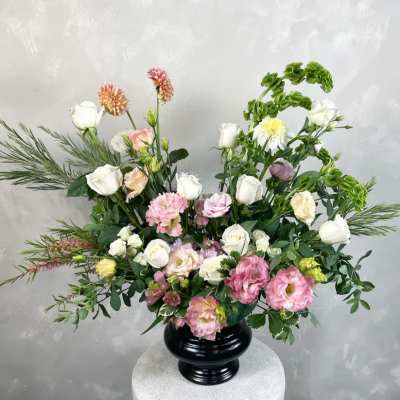 Pink and white floral arrangement in a black vase