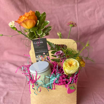 Gift bag with small flowers, a candle jar, and a card