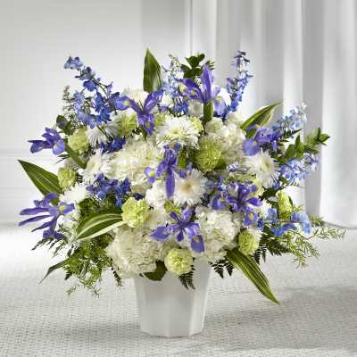 Large blue iris, white mum, and green carnation arrangement in a white vase