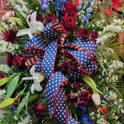 Large floral standing spray with red, white, and blue flowers and an American flag ribbon