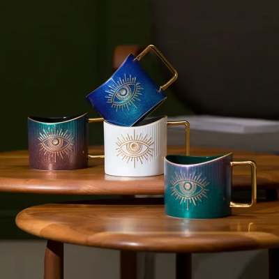 Four decorative mugs with gold handles and eye designs on a wooden table