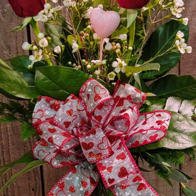 Red roses in a glass vase with a heart ribbon