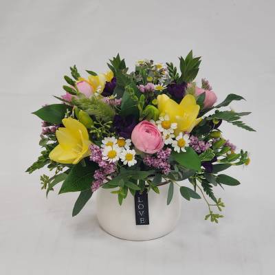 Mixed bouquet of yellow and pink flowers in a white vase