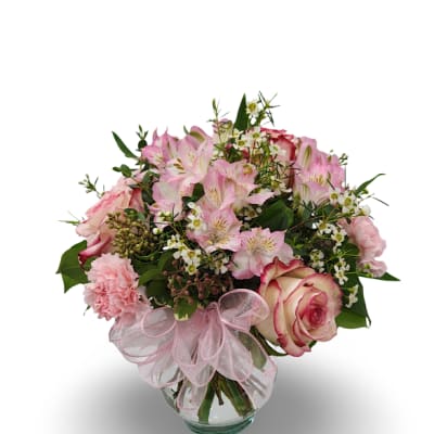Pink mixed flower bouquet in a glass vase with a pink ribbon