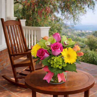 Pink roses and yellow daisies in a glass vase on a table