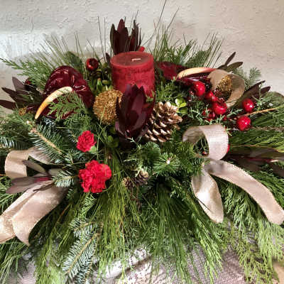 Holiday centerpiece with red candle, pinecones, ribbons, and evergreen branches