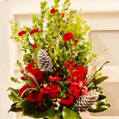 Red rose arrangement in a vase with pinecones and berries