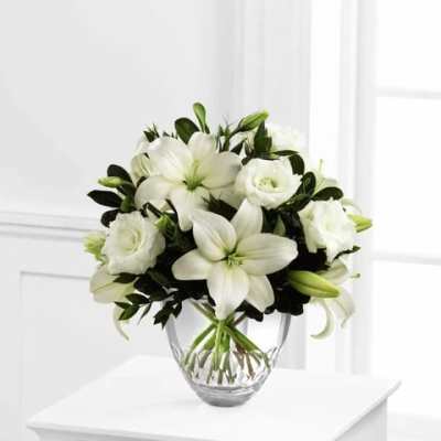 White lilies and roses in a clear glass vase